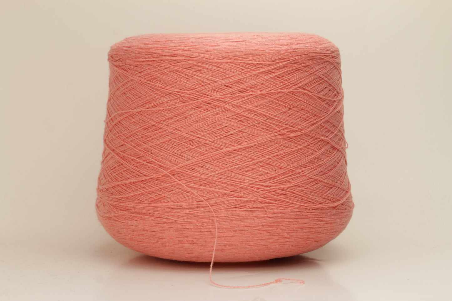 Close-up of soft, two-ply cashmere yarn in a delicate, even pink shade, showcasing its fine, slightly fuzzy texture and subtle sheen.