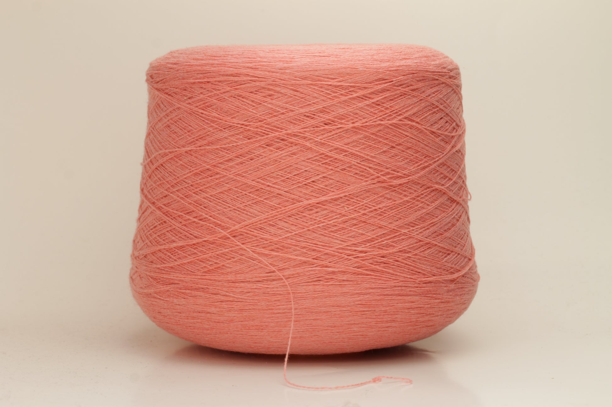 Close-up of soft, two-ply cashmere yarn in a delicate, even pink shade, showcasing its fine, slightly fuzzy texture and subtle sheen.