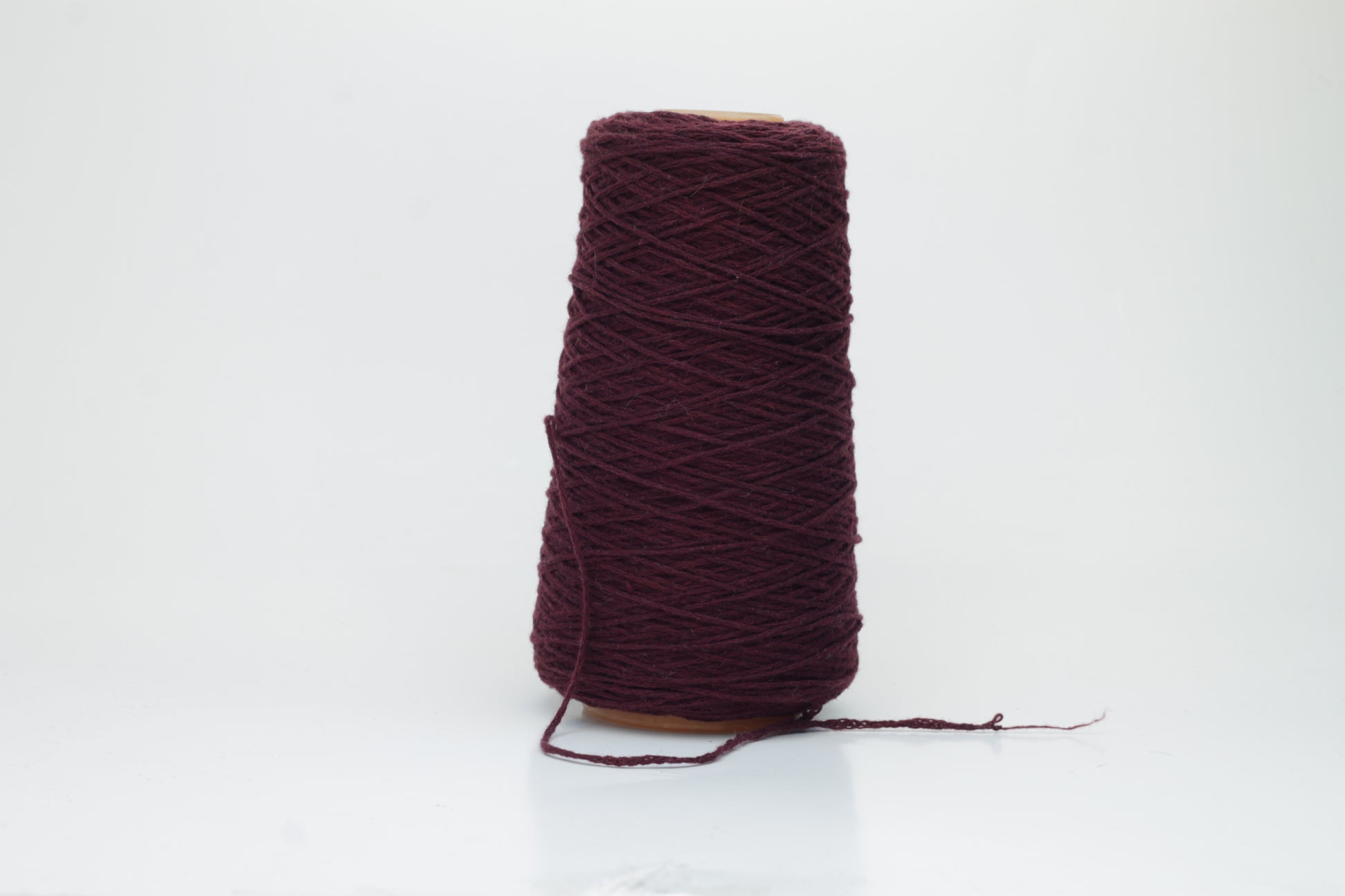 A vibrant bouganville single-ply cashmere yarn, softly twisted with a delicate halo, exhibiting a luxurious, deep pink-purple hue.