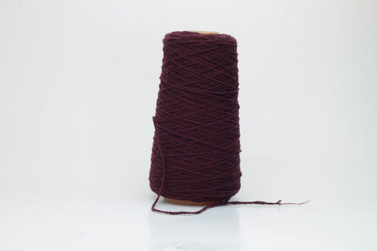 A vibrant bouganville single-ply cashmere yarn, softly twisted with a delicate halo, exhibiting a luxurious, deep pink-purple hue.