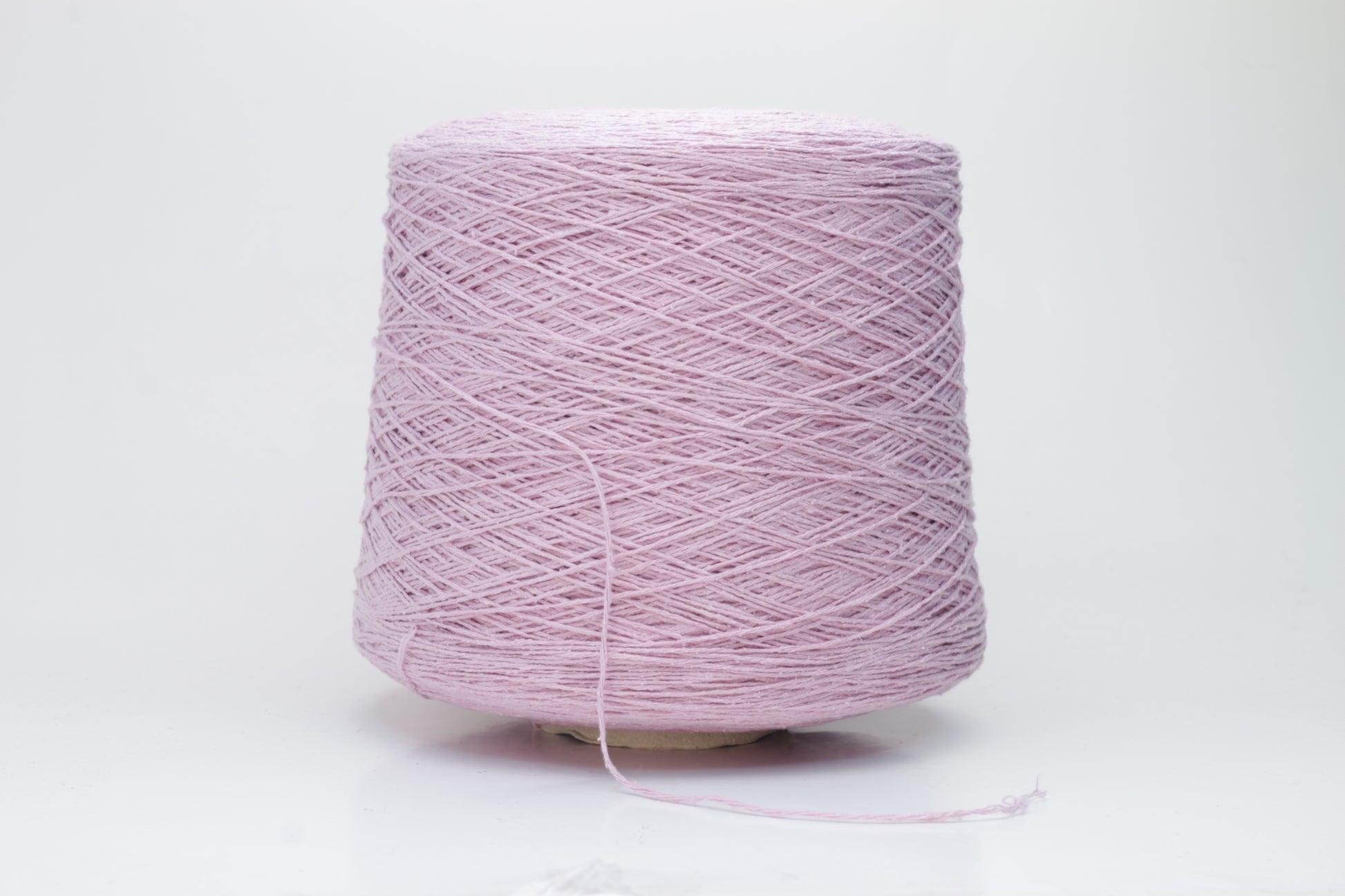 Close-up of luxurious silk bourette yarn in a vibrant 'Rosa Antic' shade. The thread exhibits a fine ply twist with a subtle sheen and remarkable fluffiness, showcasing the yarn’s rich color depth.