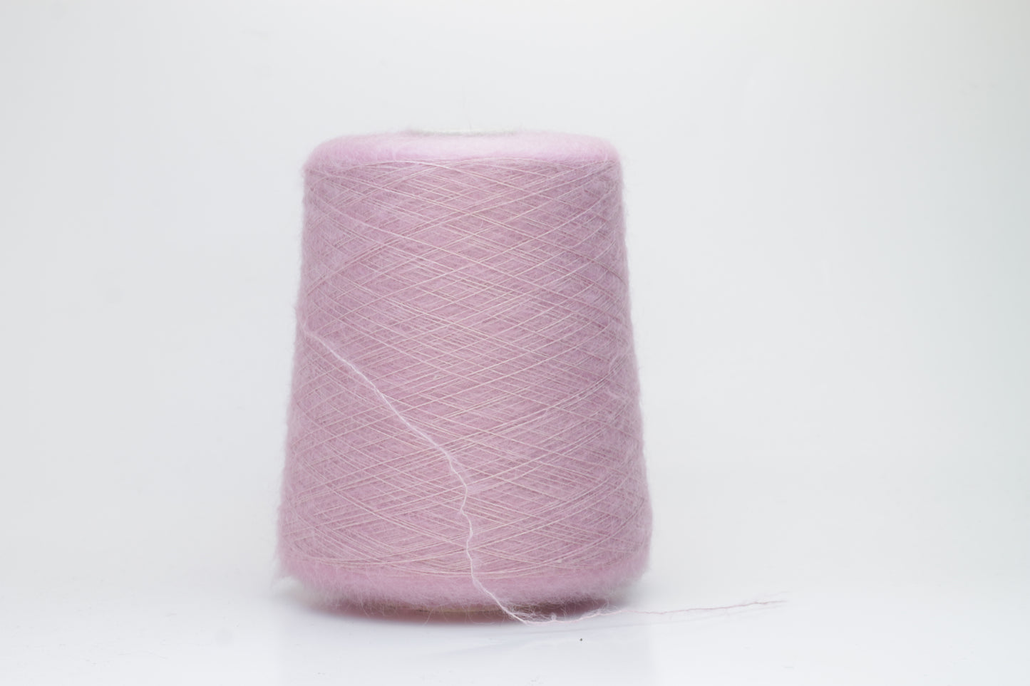 Close-up of fluffy Rosa kid mohair and silk blend yarn, subtly lustrous with a soft halo, gently twisted into a fine, delicate thread.