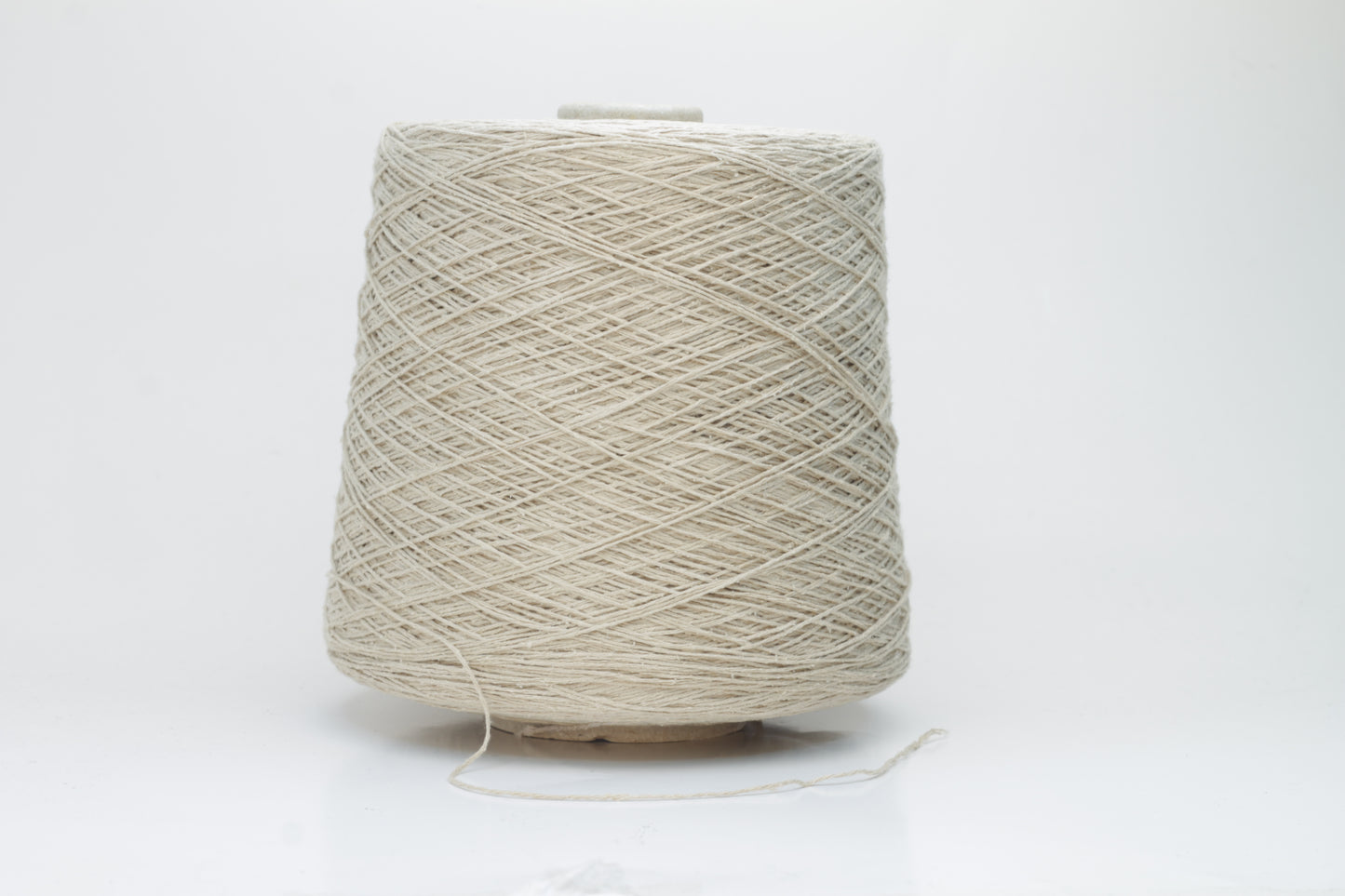 Close-up of a skein of natural beige 100% silk bourette yarn, showing its characteristic slubby, textured, slightly uneven threads.