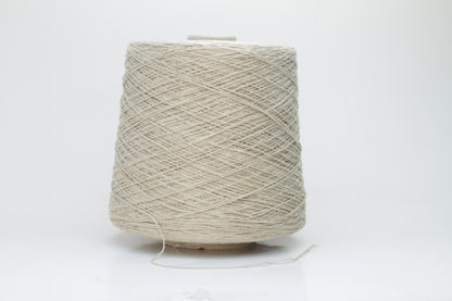 Close-up of a skein of natural beige 100% silk bourette yarn, showing its characteristic slubby, textured, slightly uneven threads.