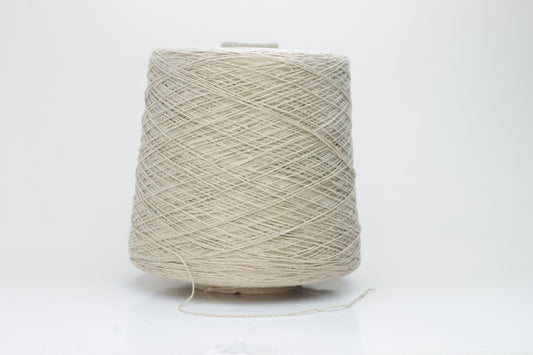 Close-up of a skein of natural beige 100% silk bourette yarn, showing its characteristic slubby, textured, slightly uneven threads.
