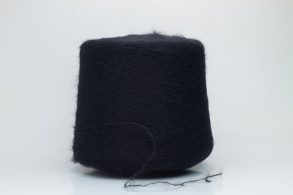 Close-up of fluffy Black kid mohair and silk blend yarn, subtly lustrous with a soft halo, gently twisted into a fine, delicate thread.