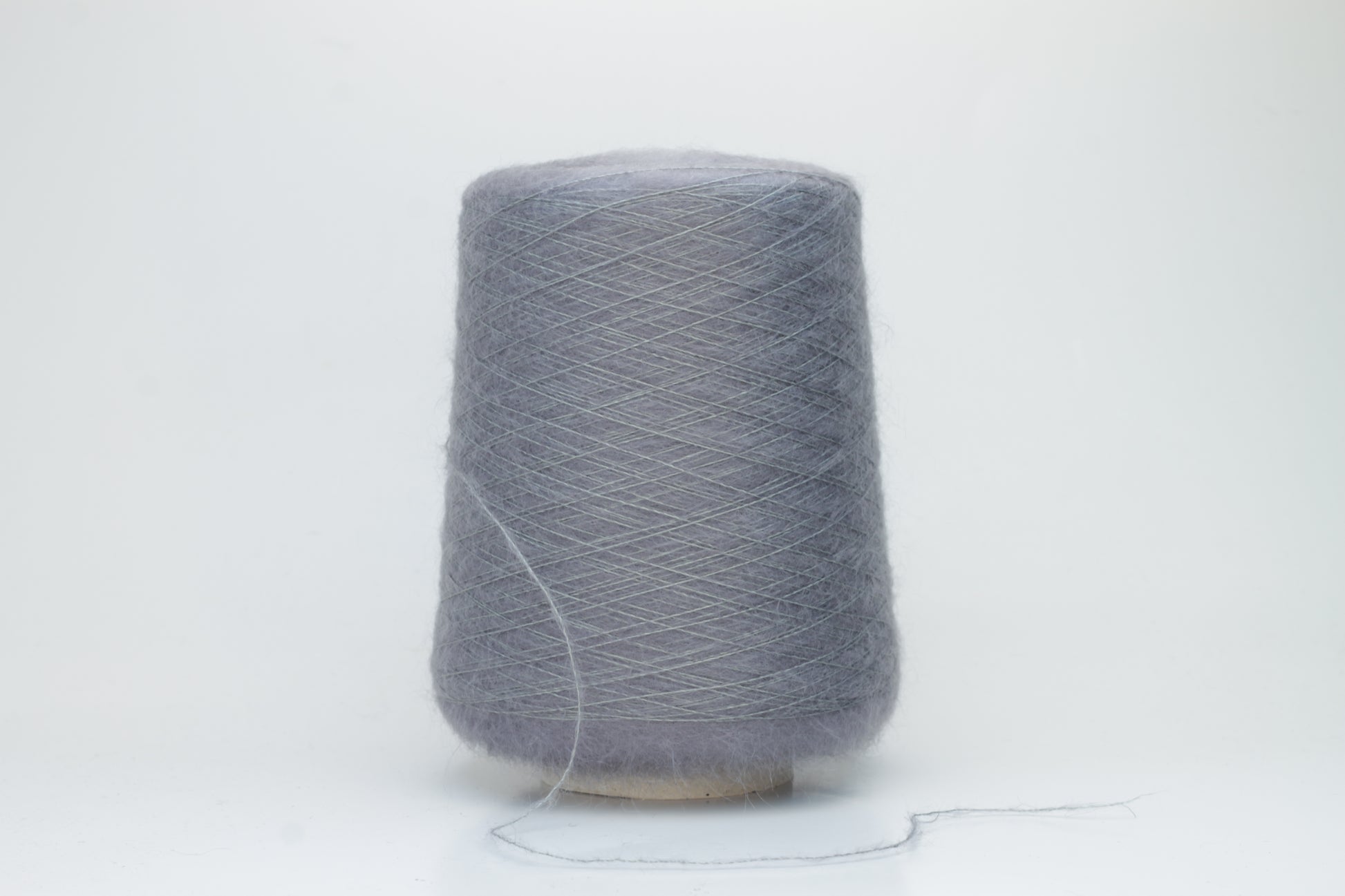 Close-up of fluffy Smog (Gray) kid mohair and silk blend yarn, subtly lustrous with a soft halo, gently twisted into a fine, delicate thread.
