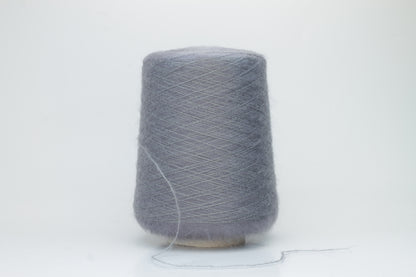 Close-up of fluffy Smog (Gray) kid mohair and silk blend yarn, subtly lustrous with a soft halo, gently twisted into a fine, delicate thread.
