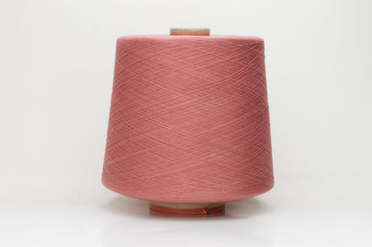 A close-up shows a finely twisted 2-ply strand of soft cotton yarn in a muted dusty rose pink, exhibiting a subtle, even texture and a delicate, gentle sheen.