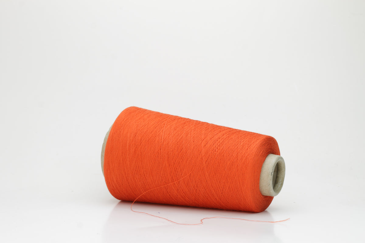 Close-up of a vibrant Mandarin Orange cotton yarn cone, revealing its smooth, tightly twisted single ply and subtle natural sheen.