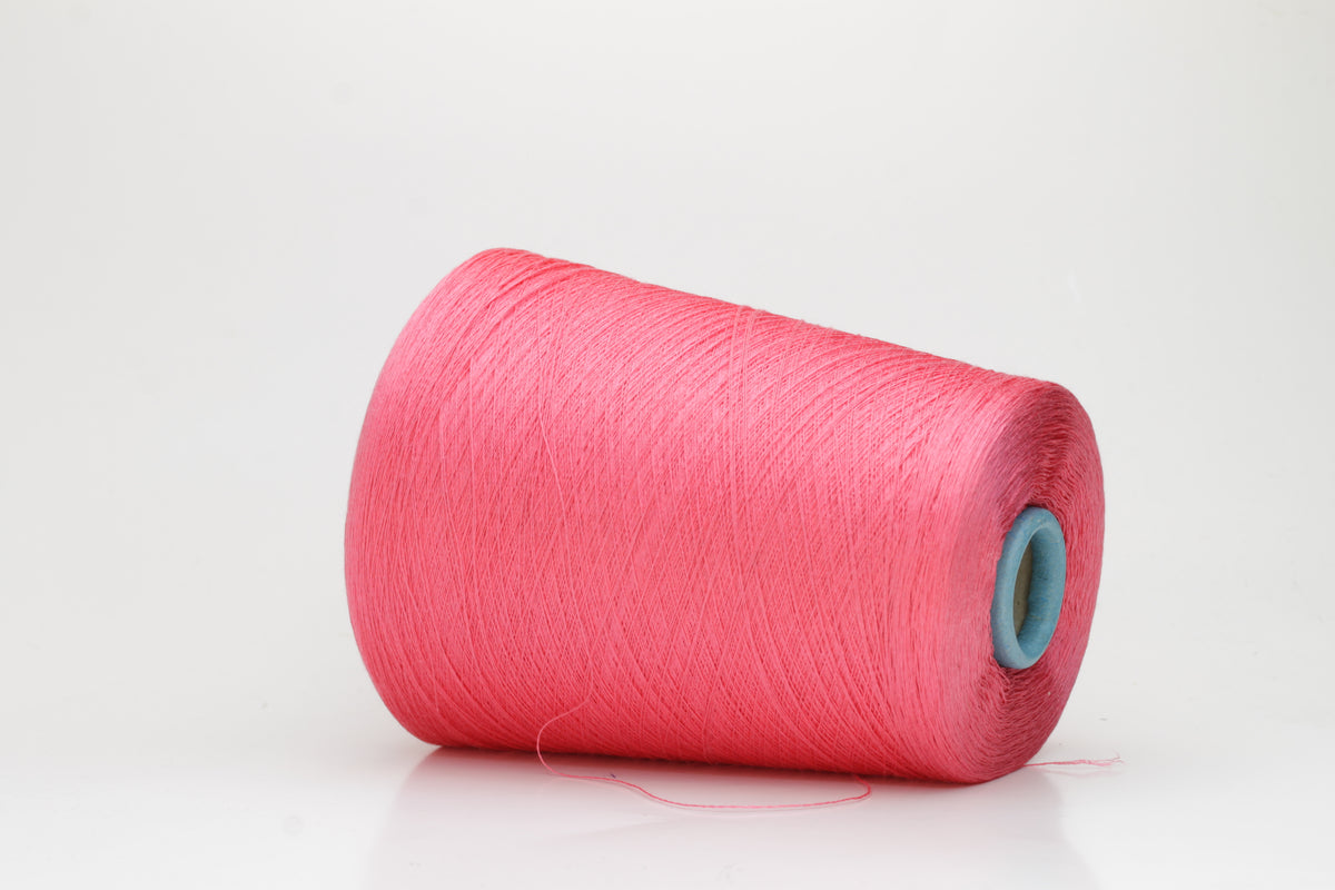 Close-up of a single ply, highly lustrous, smooth bright coral pink silk yarn with a subtle, delicate twist. The color is deep and vibrant.