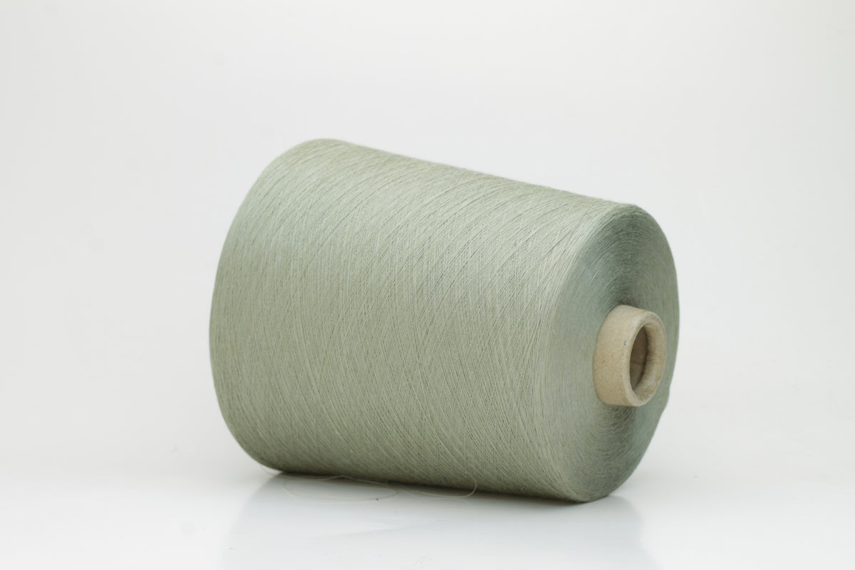 A finely spun, lustrous two-ply cotton yarn in a muted, earthy soft sage green, showcasing a gentle twist and smooth finish.