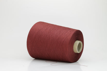 Close-up of a tightly twisted, matte finish cotton yarn in a rich, earthy warm terracotta hue, showcasing its smooth texture and consistent ply structure, ready for crafting.