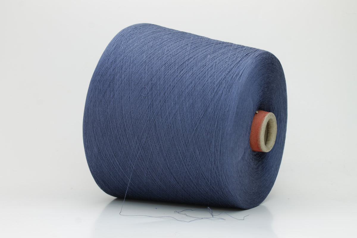 Close-up of finely spun, matte-finish cotton yarn in a rich, multi-toned classic denim blue heather, revealing subtle variations and a smooth, consistent two-ply twist.