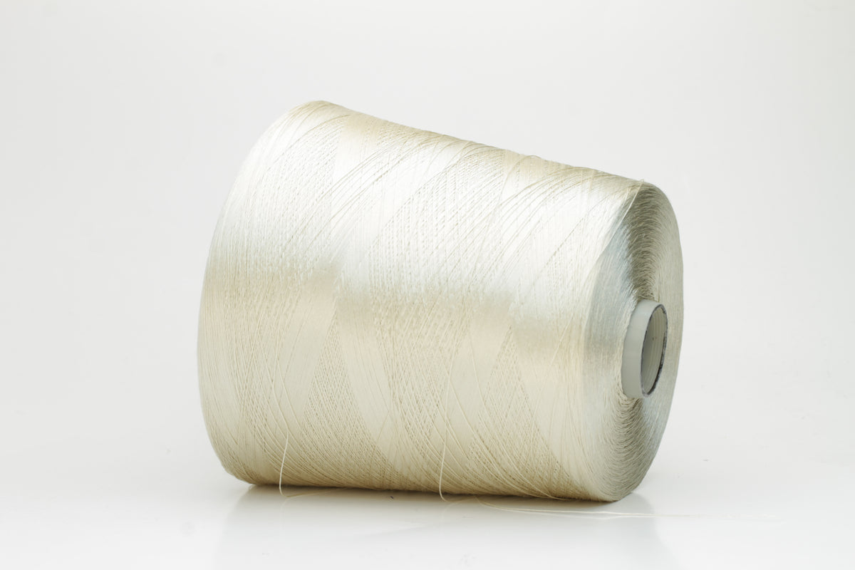 Close-up of finely plied natural silk yarn in a pale, warm champagne tone, reflecting light with a soft, radiant shimmer.