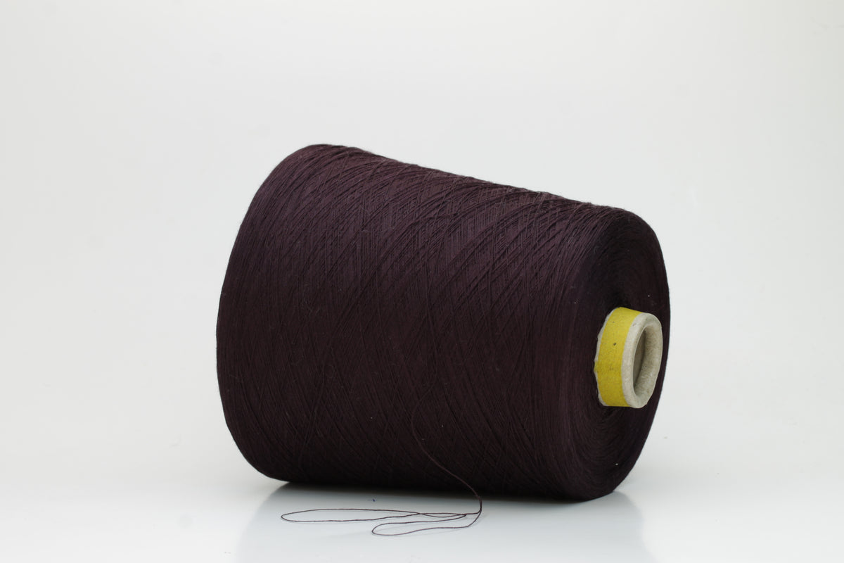 Close-up of a tightly wound cone of smooth, fine cotton yarn in a rich, deep eggplant color, showing a subtle sheen and even 3-ply twist.