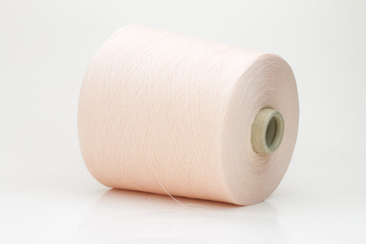 Close-up of finely spun, delicate powder pink cotton yarn, showcasing its soft, matte finish and subtle, even twist with excellent stitch definition.