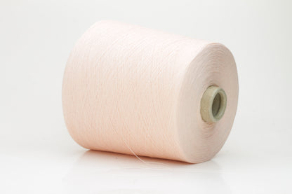 Close-up of finely spun, delicate powder pink cotton yarn, showcasing its soft, matte finish and subtle, even twist with excellent stitch definition.