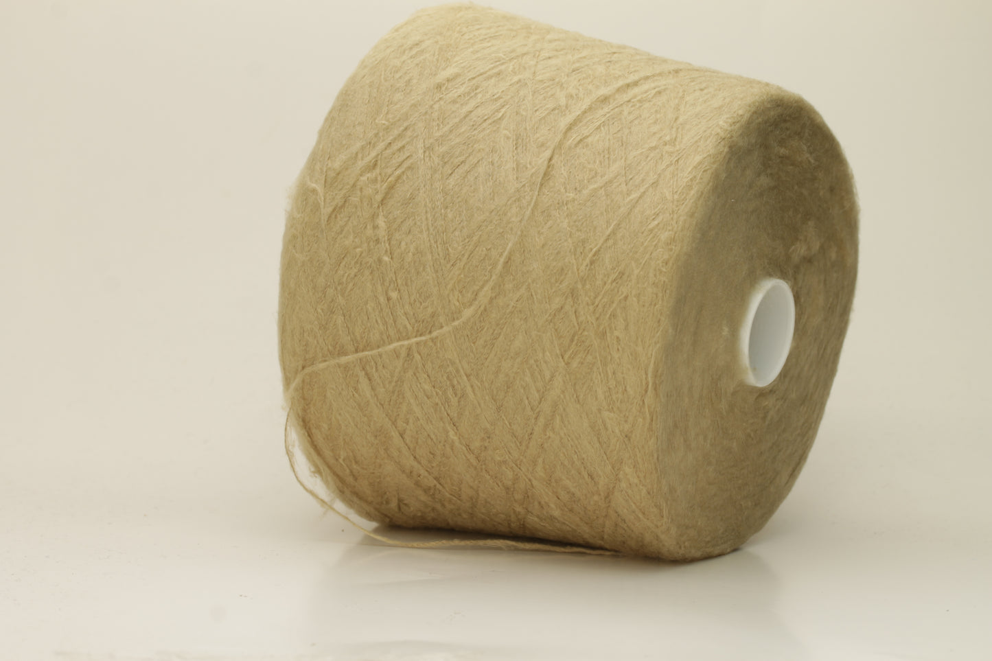 Luxurious, pristine Beige single-ply silk yarn with a smooth, uniform texture and a delicate sheen, softly coiled.