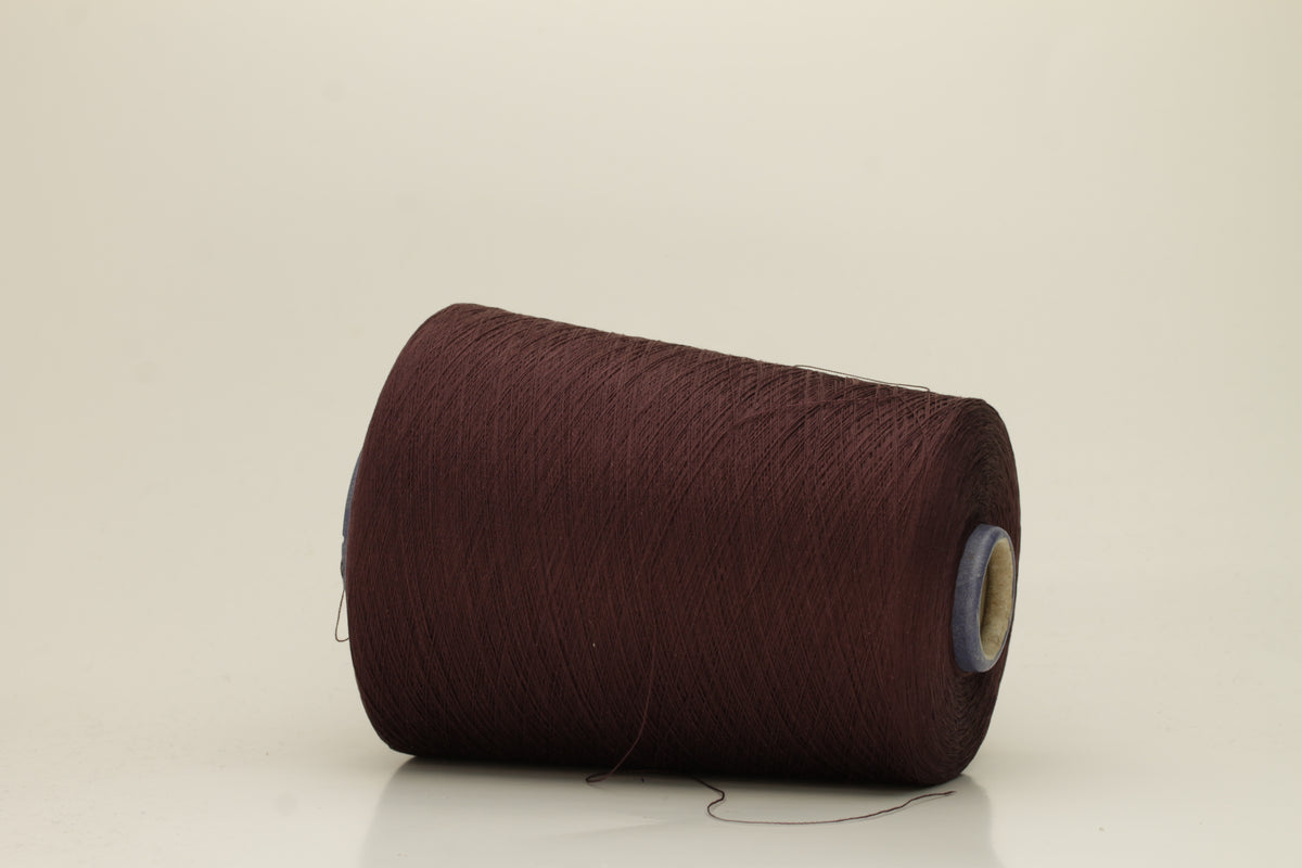 Close-up of a deep, rich espresso brown silk yarn wound in a neat cake, showcasing its smooth, lustrous surface and fine, even ply twist. The individual strands reflect light softly.