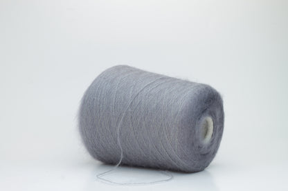 Close-up of fluffy Smog (Gray) kid mohair and silk blend yarn, subtly lustrous with a soft halo, gently twisted into a fine, delicate thread.