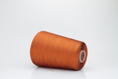Close-up of a meticulously spun, single-ply bright orange silk yarn with a crisp, almost translucent quality and brilliant sheen.