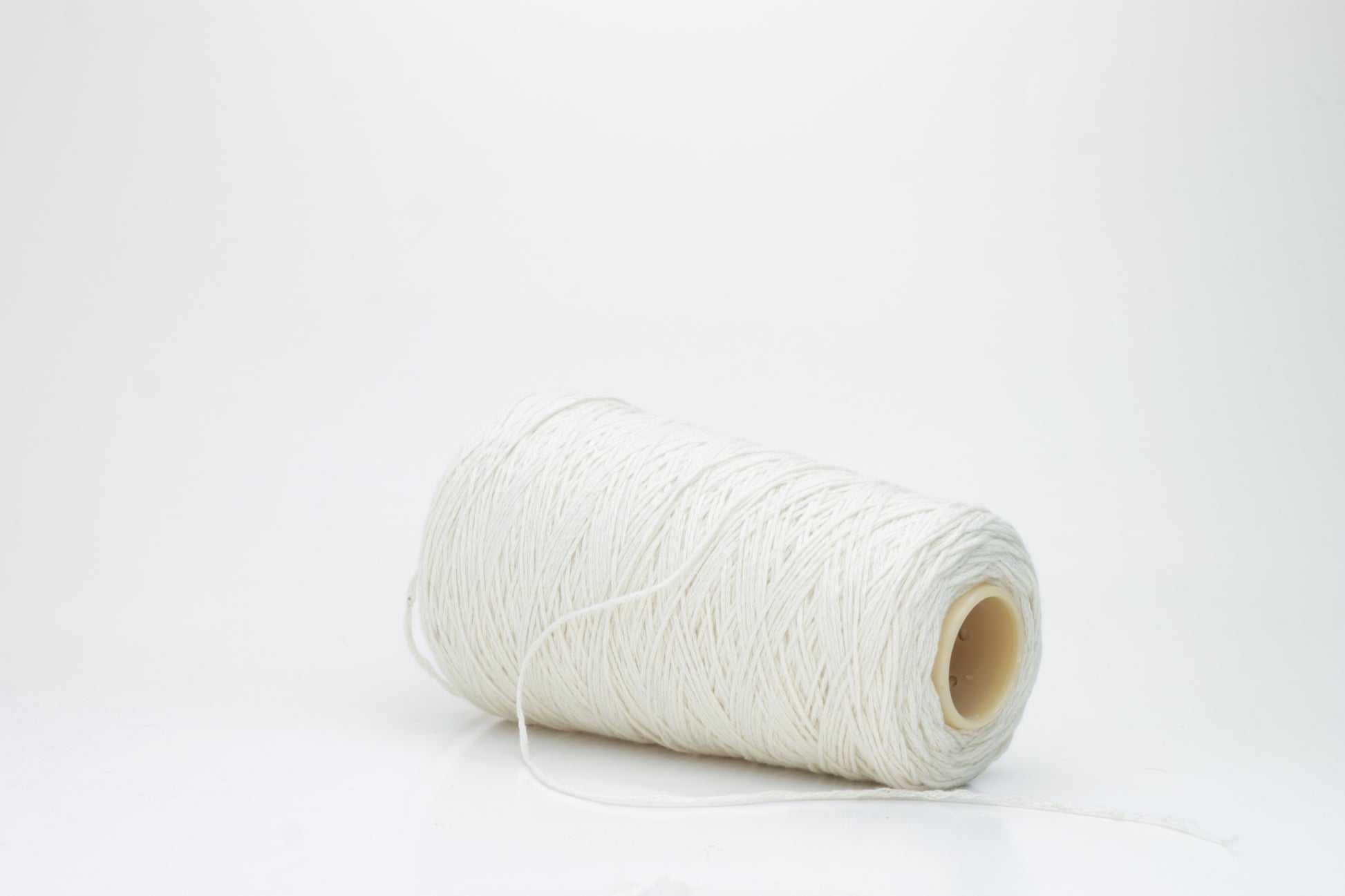 Single-ply, exceptionally fine cashmere yarn in a soft, undyed natural cream hue with a subtle, silky sheen and gentle fluffiness.