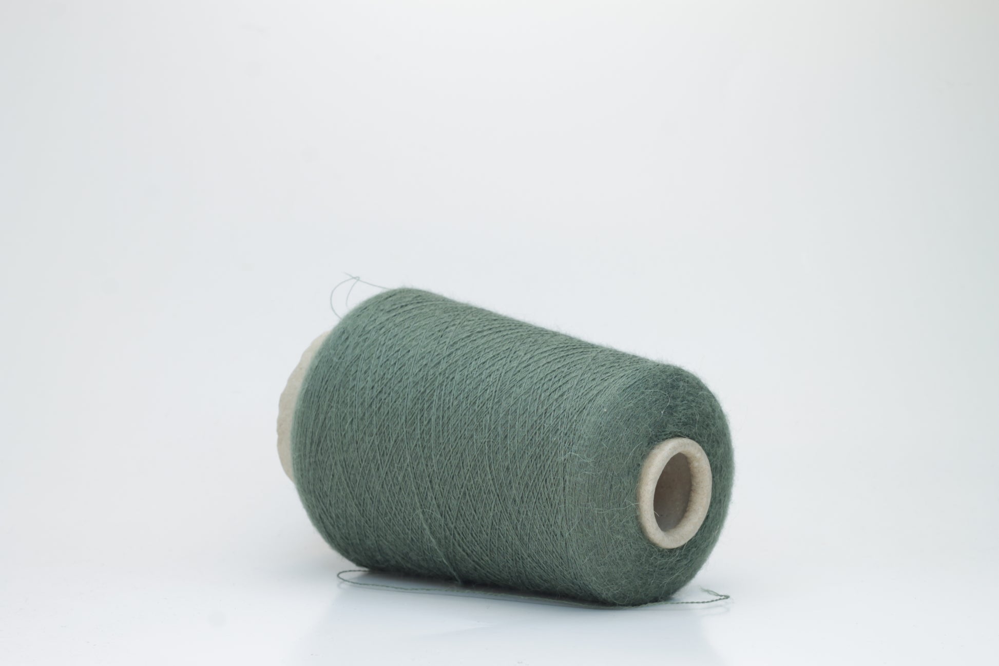 Close-up of a skein of soft, plied alpaca merino yarn in a deep green, showing subtle sheen and fine fiber halo.