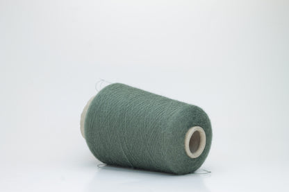 Close-up of a skein of soft, plied alpaca merino yarn in a deep green, showing subtle sheen and fine fiber halo.