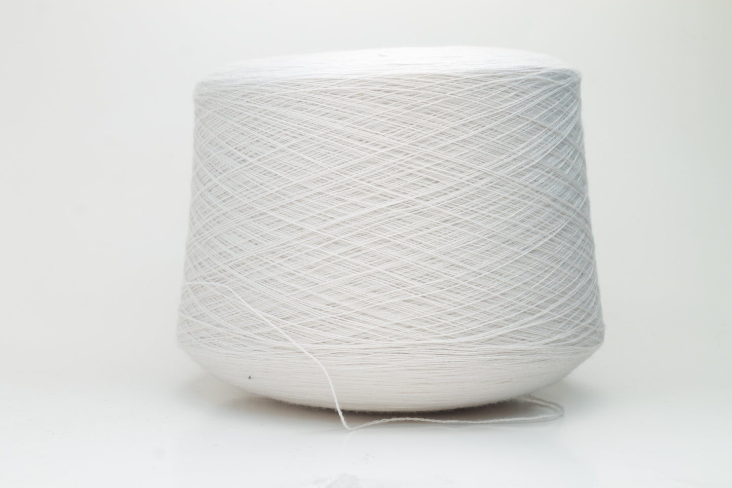 Close-up shot of creamy white Zegna Baruffa merino yarn, showcasing a dense, twisted ply structure and subtle sheen, with a fluffy texture inviting tactile exploration.
