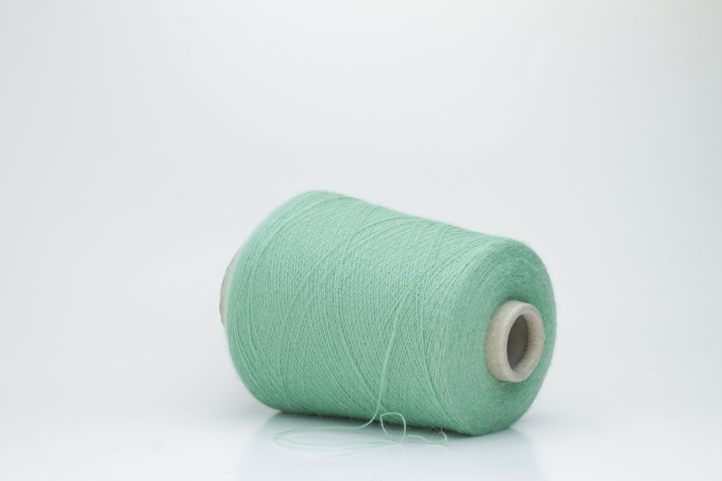 Close-up of a skein of soft, plied alpaca merino yarn in a deep green, showing subtle sheen and fine fiber halo.