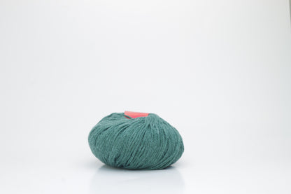 Close-up of a ball of fluffy, vibrant forest green yarn with a visible soft halo, highlighting the luxurious mohair and merino fibers.
