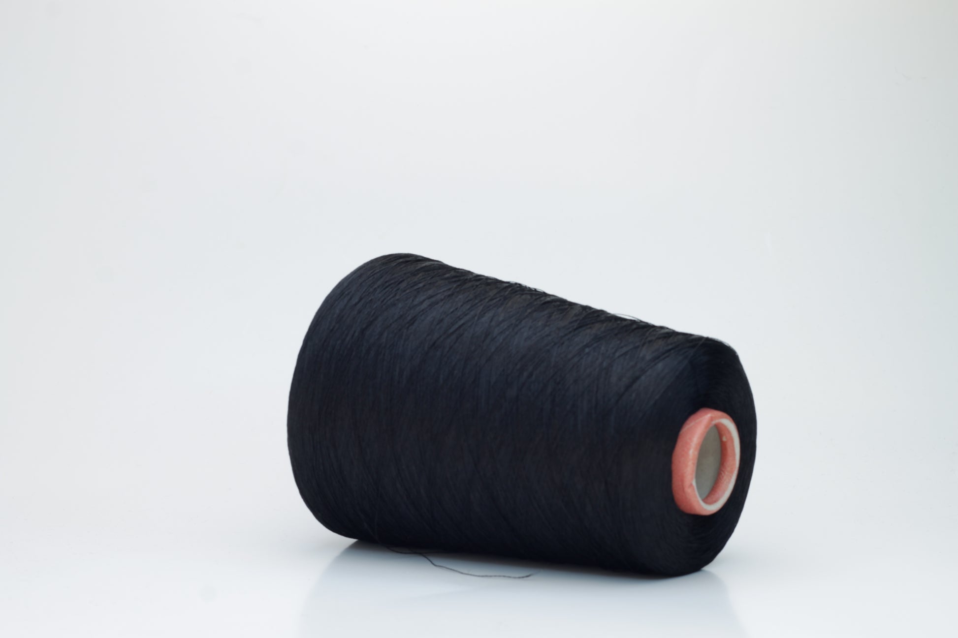 A single, tightly spun strand of incredibly fine, jet black silk yarn, showcasing a brilliant, almost glass-like sheen.