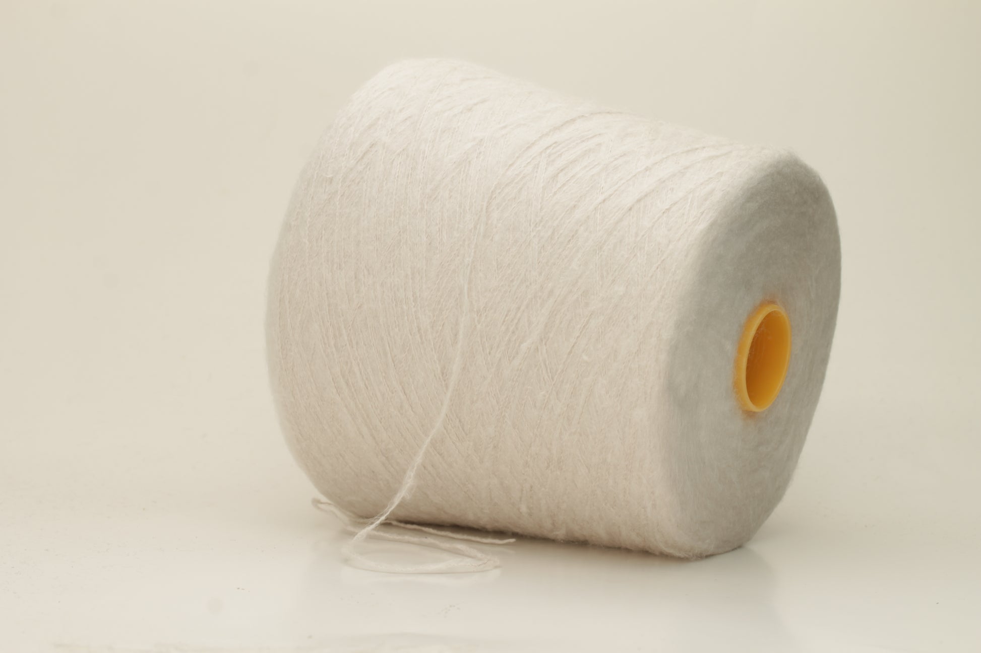 Luxurious, pristine white single-ply silk yarn with a smooth, uniform texture and a delicate sheen, softly coiled.