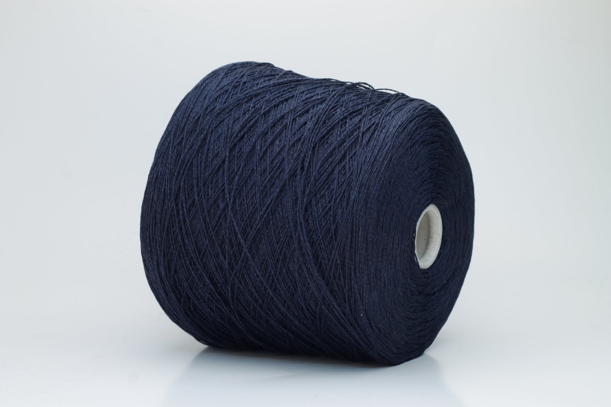 Close-up of pristine Navy linen and viscose blend yarn, softly twisted with a subtle sheen, showcasing its fine, smooth texture.