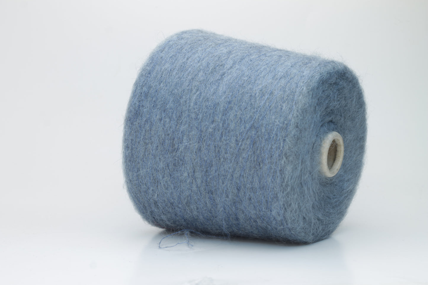 Close-up photograph showcasing a vibrant blue SuperKidMohair yarn skein, displaying a dense, fluffy texture with subtle sheen. The ply twist is evident, revealing a tightly wound thread structure.
