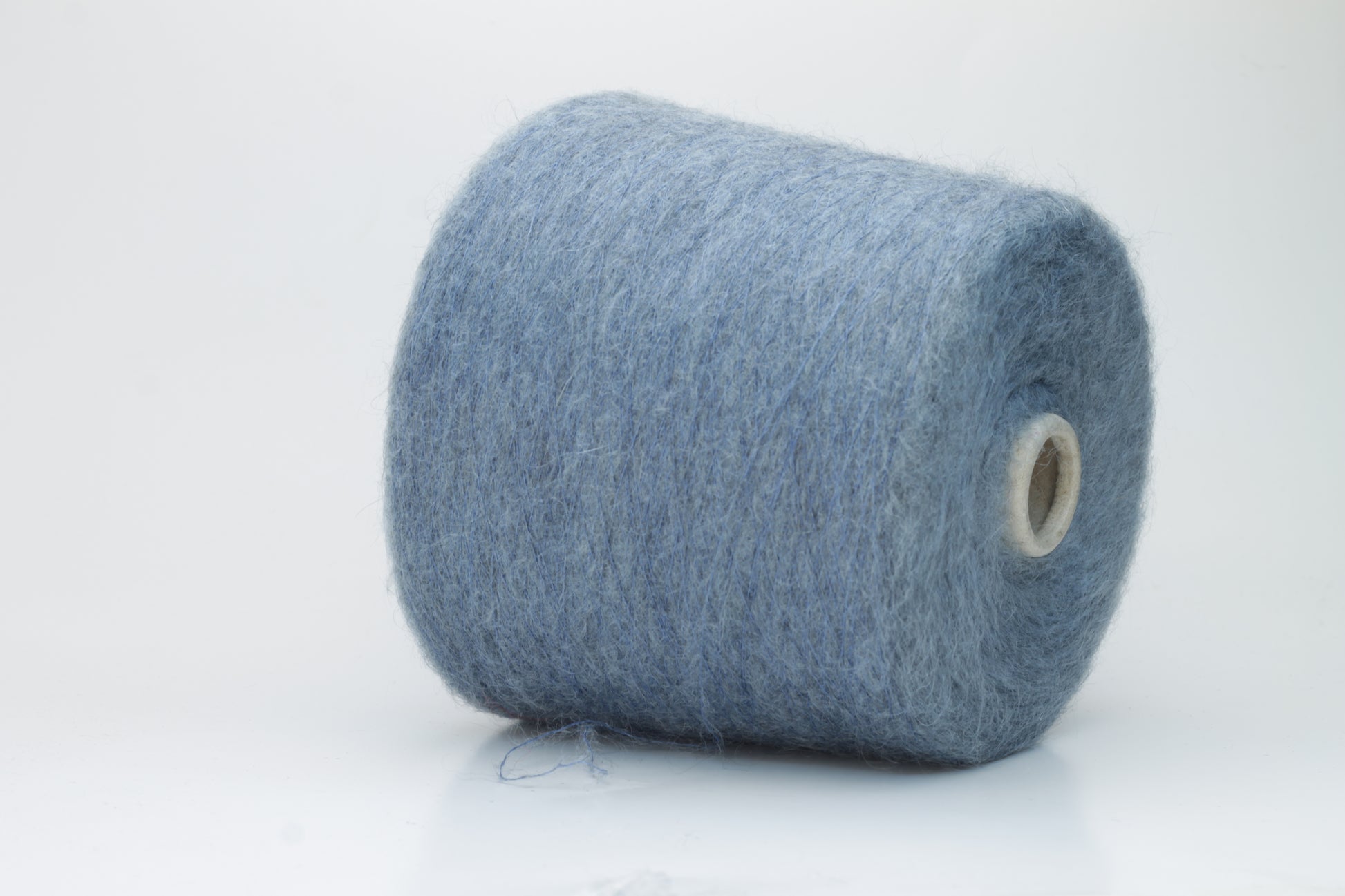 Close-up photograph showcasing a vibrant blue SuperKidMohair yarn skein, displaying a dense, fluffy texture with subtle sheen. The ply twist is evident, revealing a tightly wound thread structure.