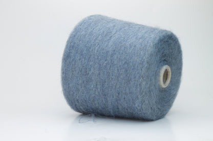 Close-up photograph showcasing a vibrant blue SuperKidMohair yarn skein, displaying a dense, fluffy texture with subtle sheen. The ply twist is evident, revealing a tightly wound thread structure.