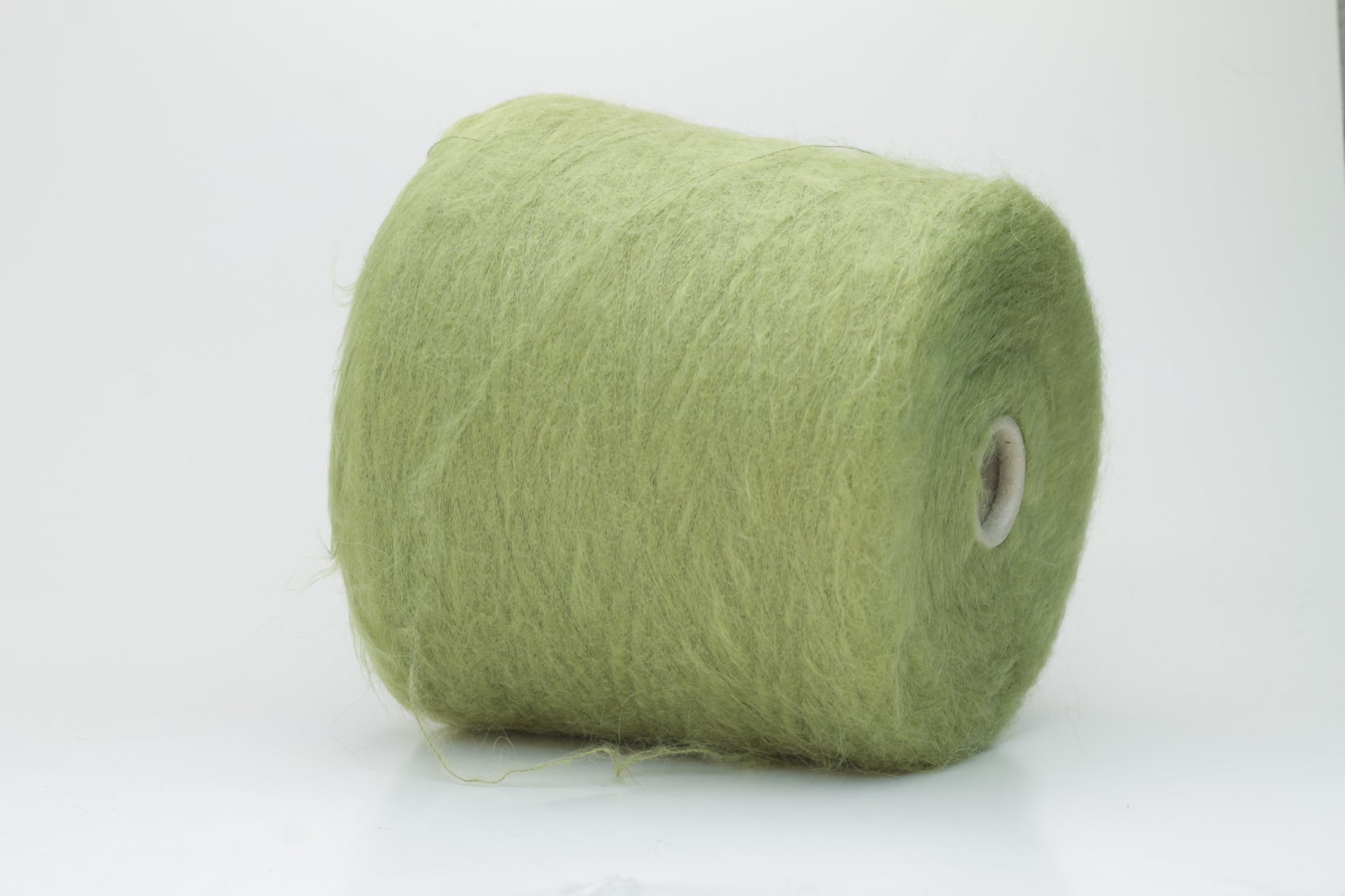 Close-up shot of vibrant green SuperKidMohair yarn showcasing a tight ply twist and rich fiber structure, revealing its inherent fluffiness and subtle sheen.
