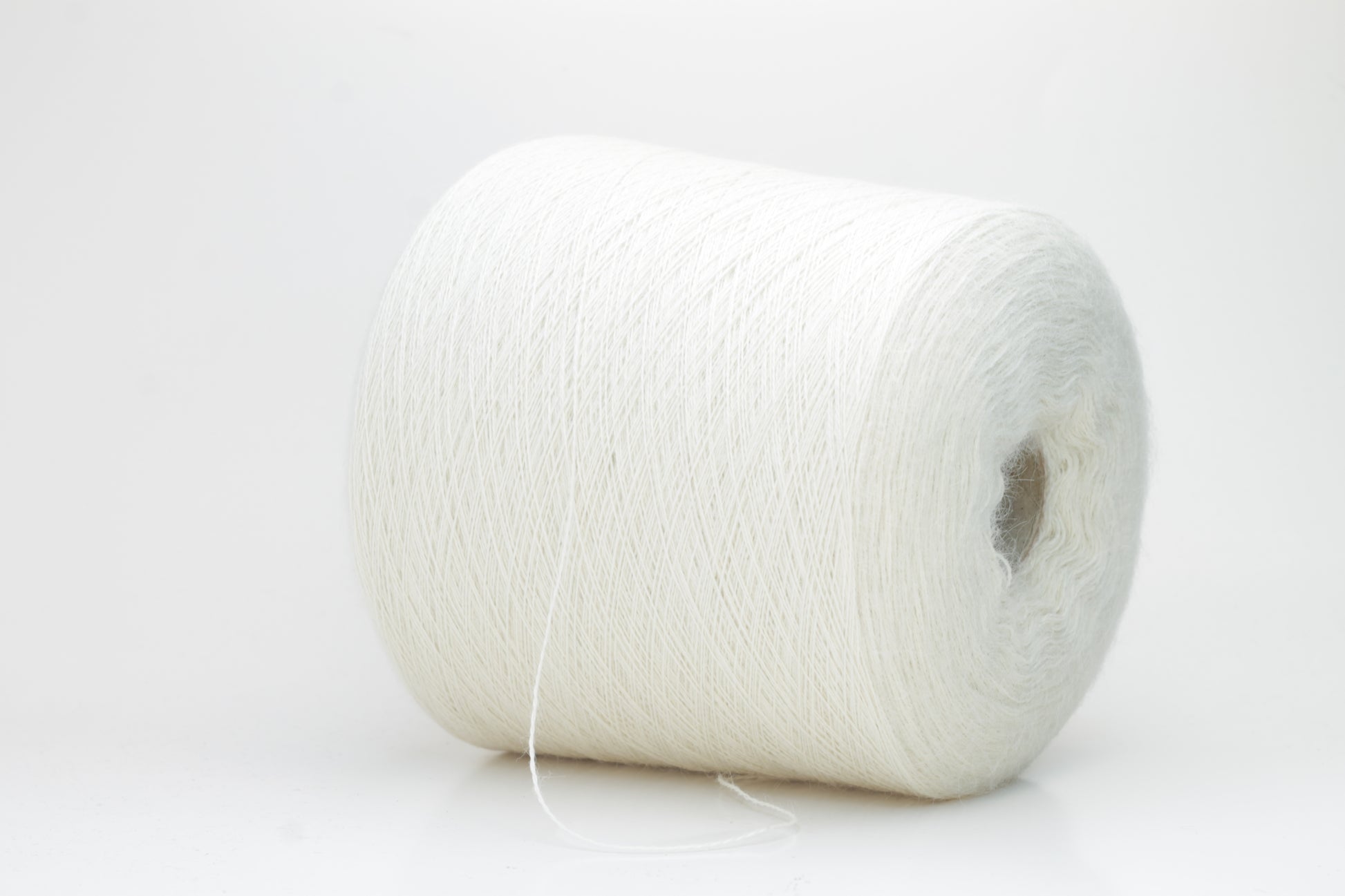 A close-up shot of a single ply, pure white alpaca yarn, softly twisted, showcasing its ethereal fluffiness and subtle sheen against a neutral background.