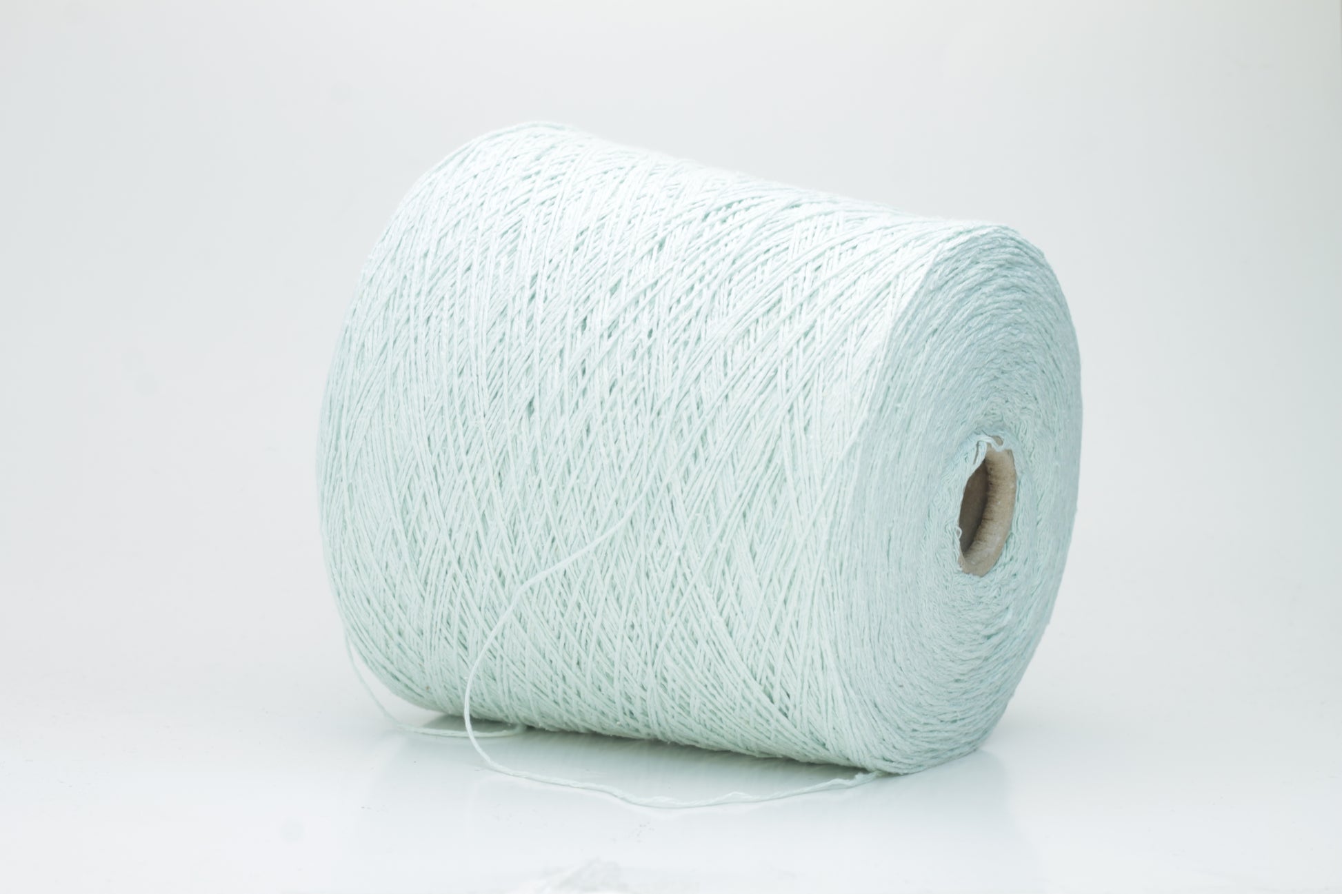 Close-up of a skein of unspun, single-ply bourette silk yarn. It has a natural, slightly textured, slubbed surface with a soft matte sheen in a serene acqua blue-green hue.