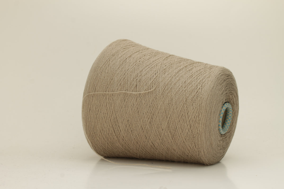 Close-up of a skein of incredibly soft, two-ply cashmere yarn in a deep, warm Mastice beige. Fine fibers with a subtle halo and elegant twist visible.