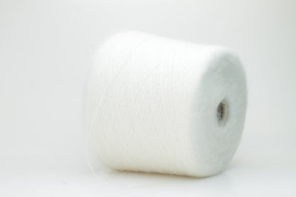 Close-up of fluffy white kid mohair and silk blend yarn, subtly lustrous with a soft halo, gently twisted into a fine, delicate thread.