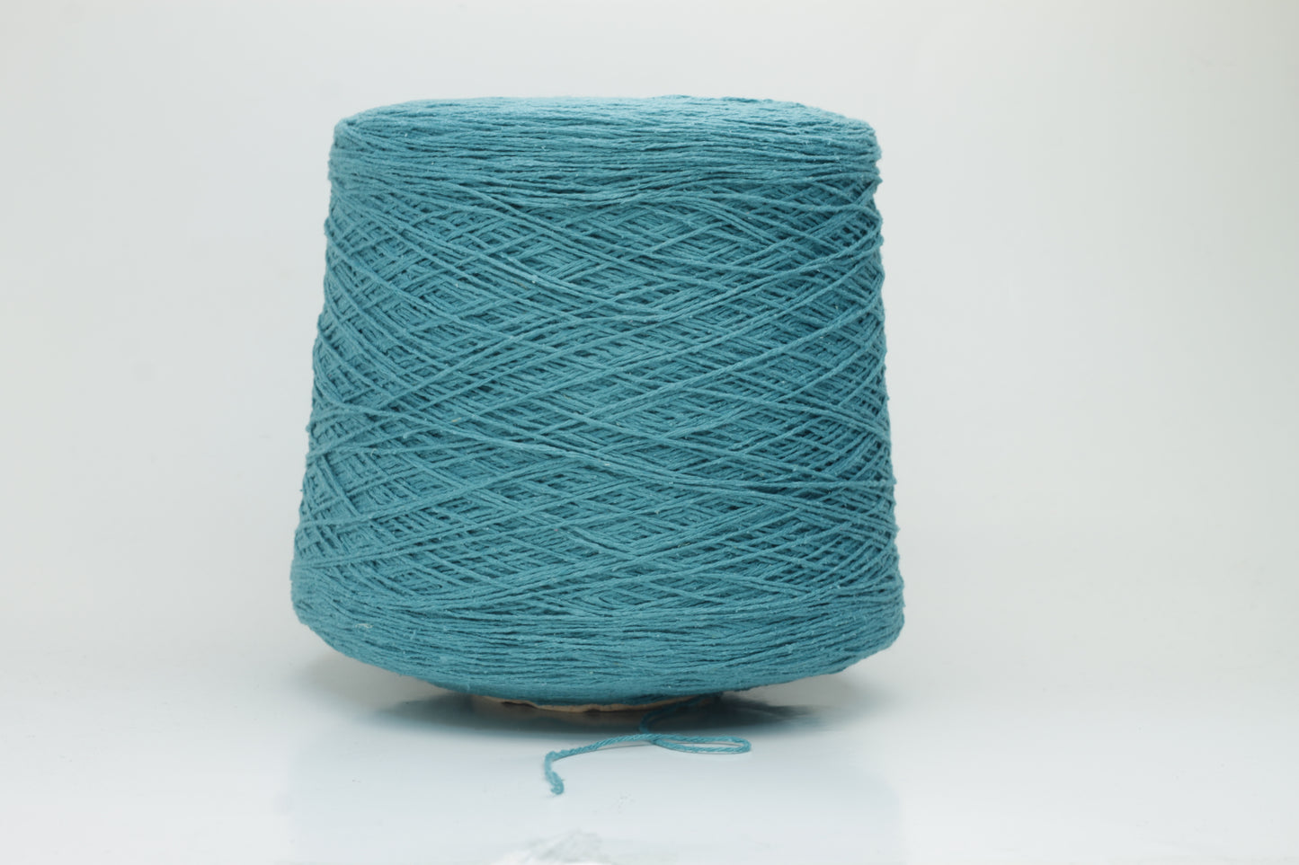Close-up of a skein of deep petrol blue-green bourette silk yarn, showing its characteristic subtle slubs and matte texture, with a gentle, soft twist.