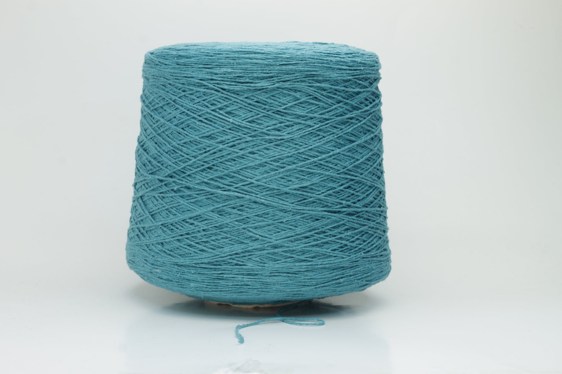 Close-up of a skein of deep petrol blue-green bourette silk yarn, showing its characteristic subtle slubs and matte texture, with a gentle, soft twist.