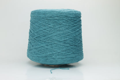 Close-up of a skein of deep petrol blue-green bourette silk yarn, showing its characteristic subtle slubs and matte texture, with a gentle, soft twist.