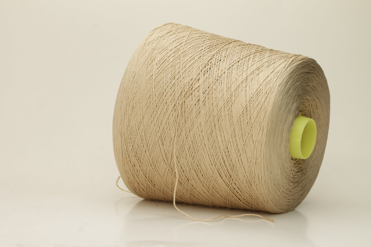 Close-up of a single strand of lustrous, fine-gauge beige silk and cotton yarn, showcasing its smooth, even twist and soft sheen.