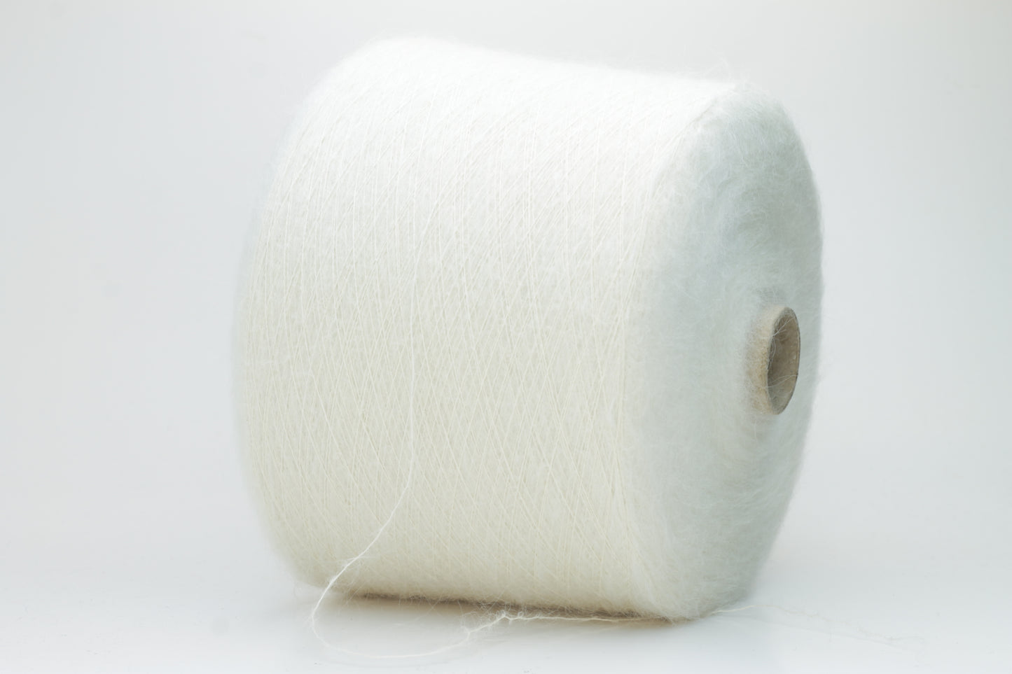 Close-up of fine white Kid Mohair and Silk yarn, exhibiting a soft, ethereal halo and subtle luminous sheen, gently twisted.
