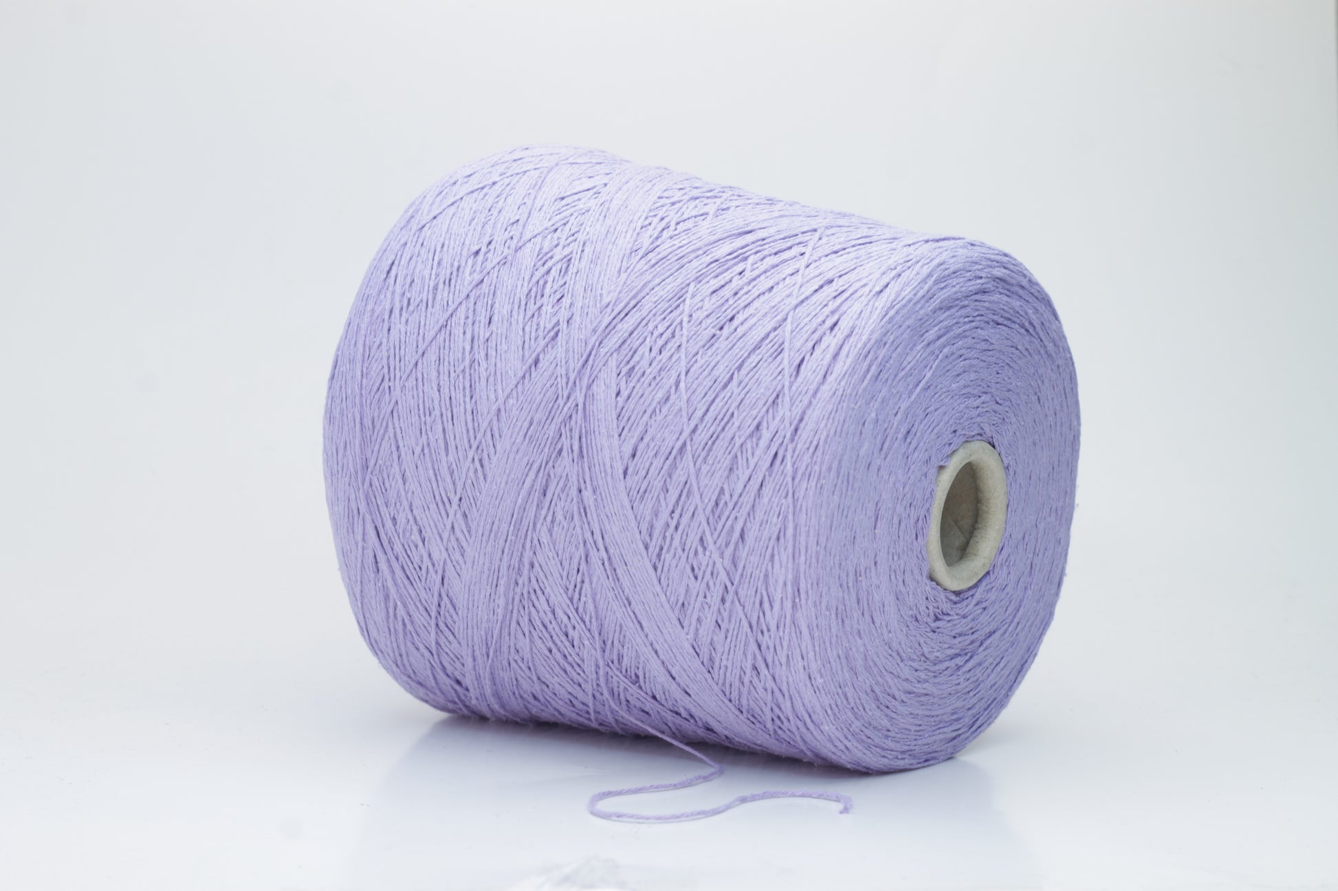 Close-up of a single strand of matte lavender silk bourette yarn, showcasing its natural slub texture and soft, nubbly appearance, coiled gently.