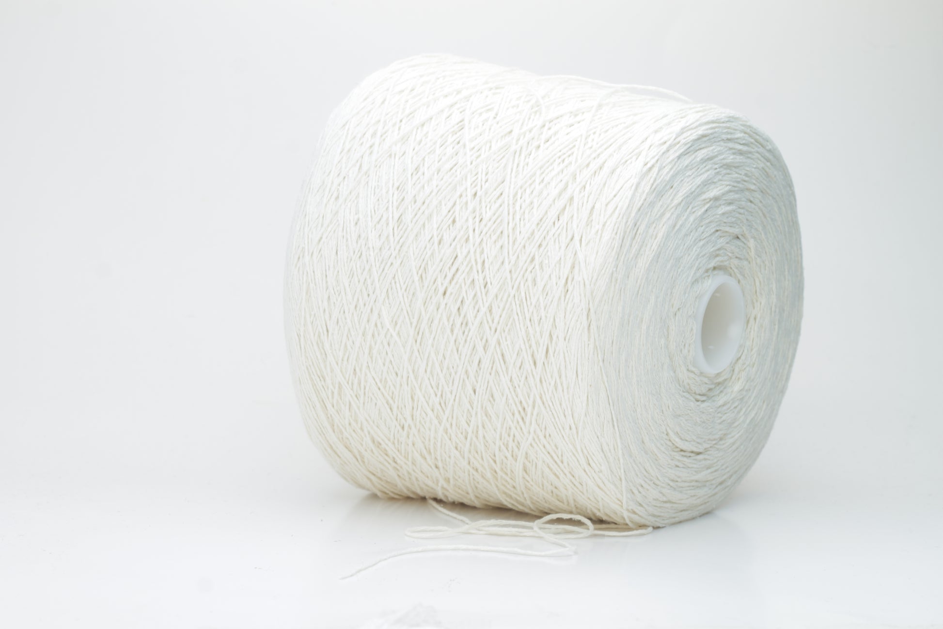 Close-up shot showcasing the fluffy, lustrous sheen of white silk bourette yarn in a single ply twist. The thread structure is clearly visible with subtle variations in color depth.